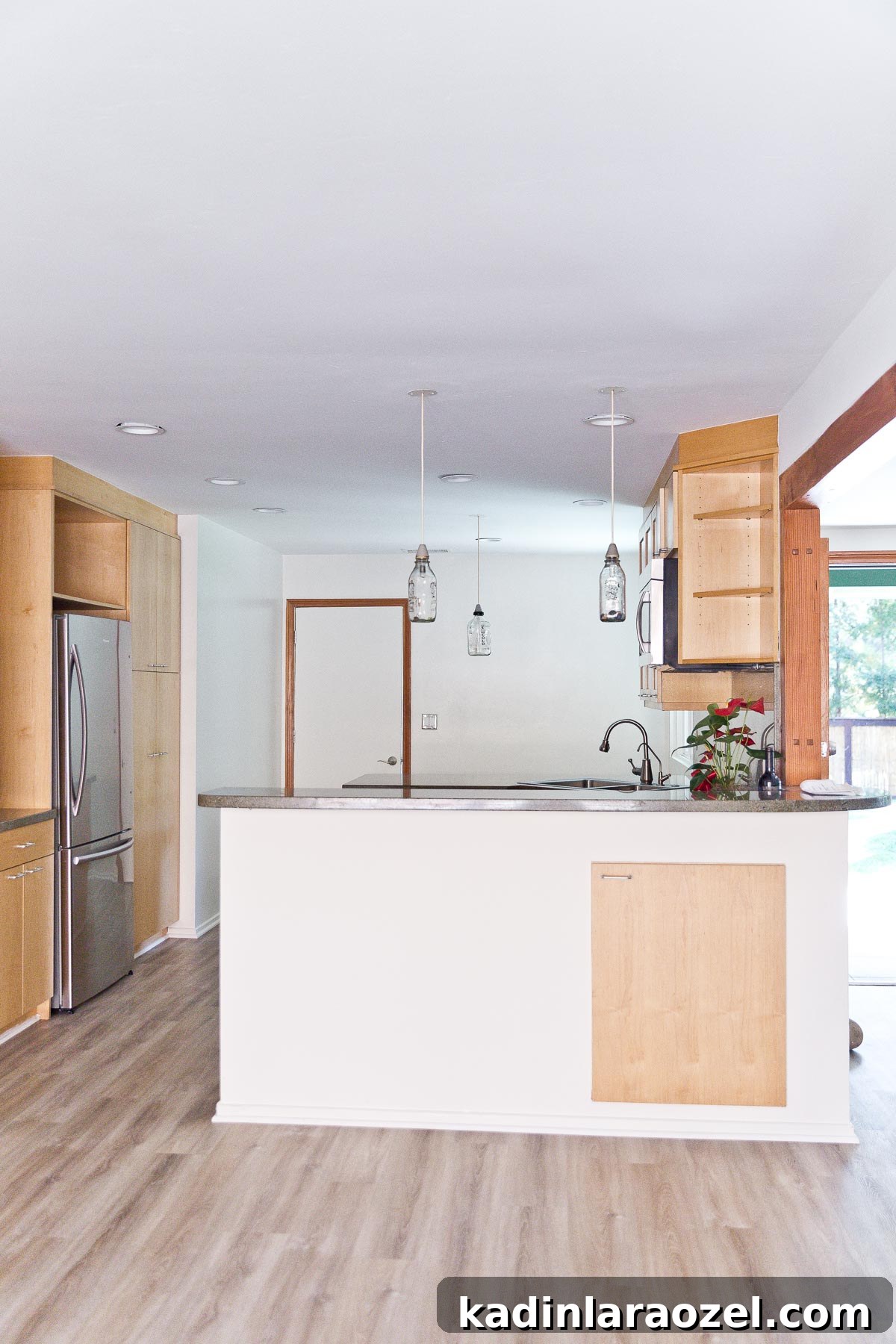 Image of empty kitchen with minimal wood cabinets and white walls.