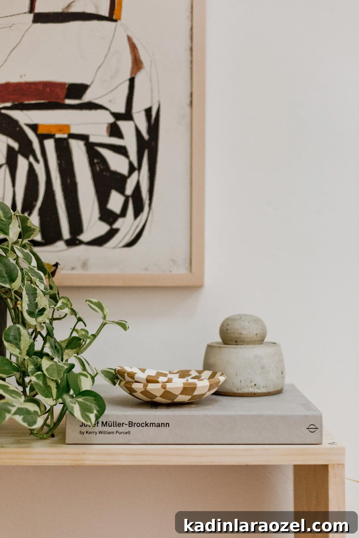 Modern, minimal table with abstract artwork and small objects.
