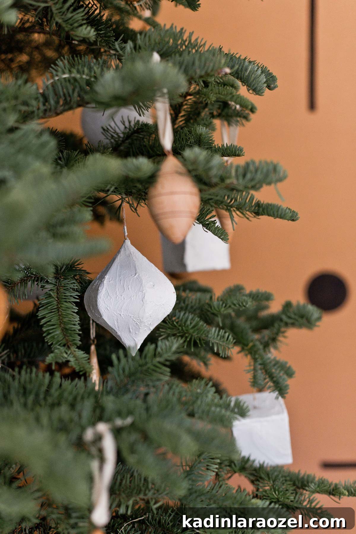 White plaster ornaments hanging on noble fir Christmas tree