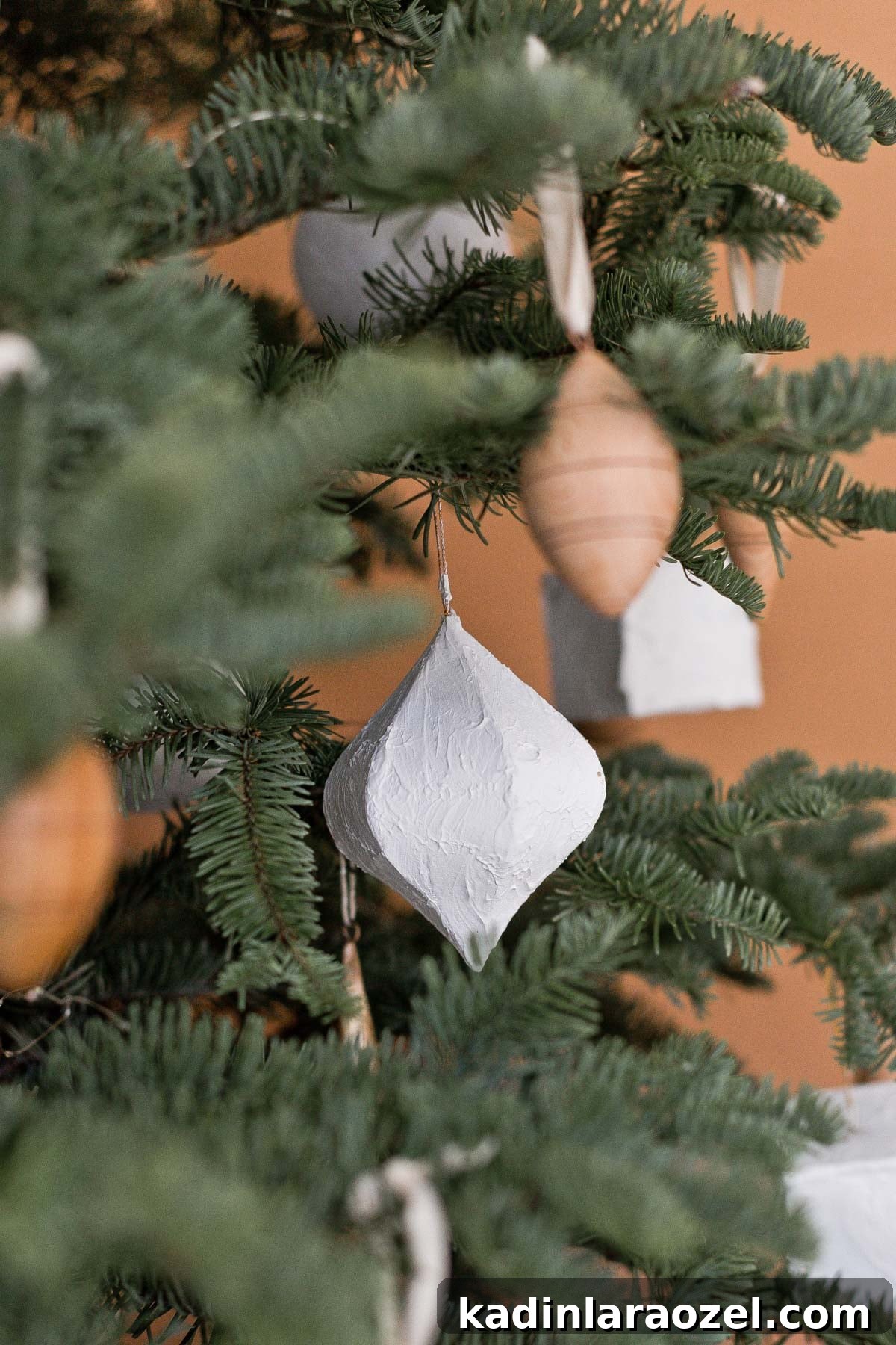 Plaster ornaments in geometric shapes hanging from Christmas tree branches