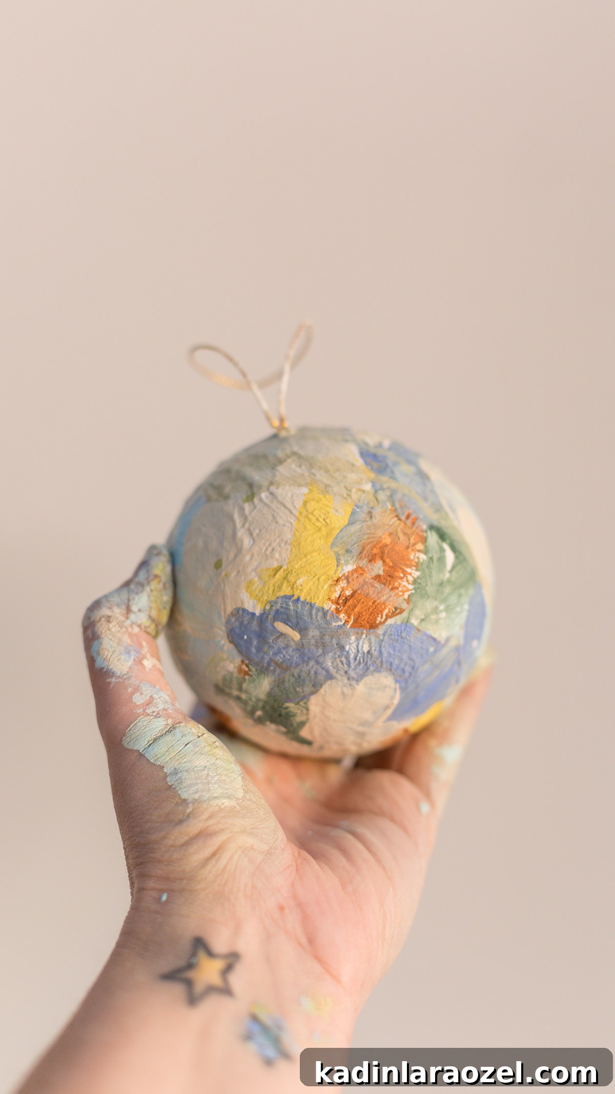 Painterly globe ornament being held in someone's hand