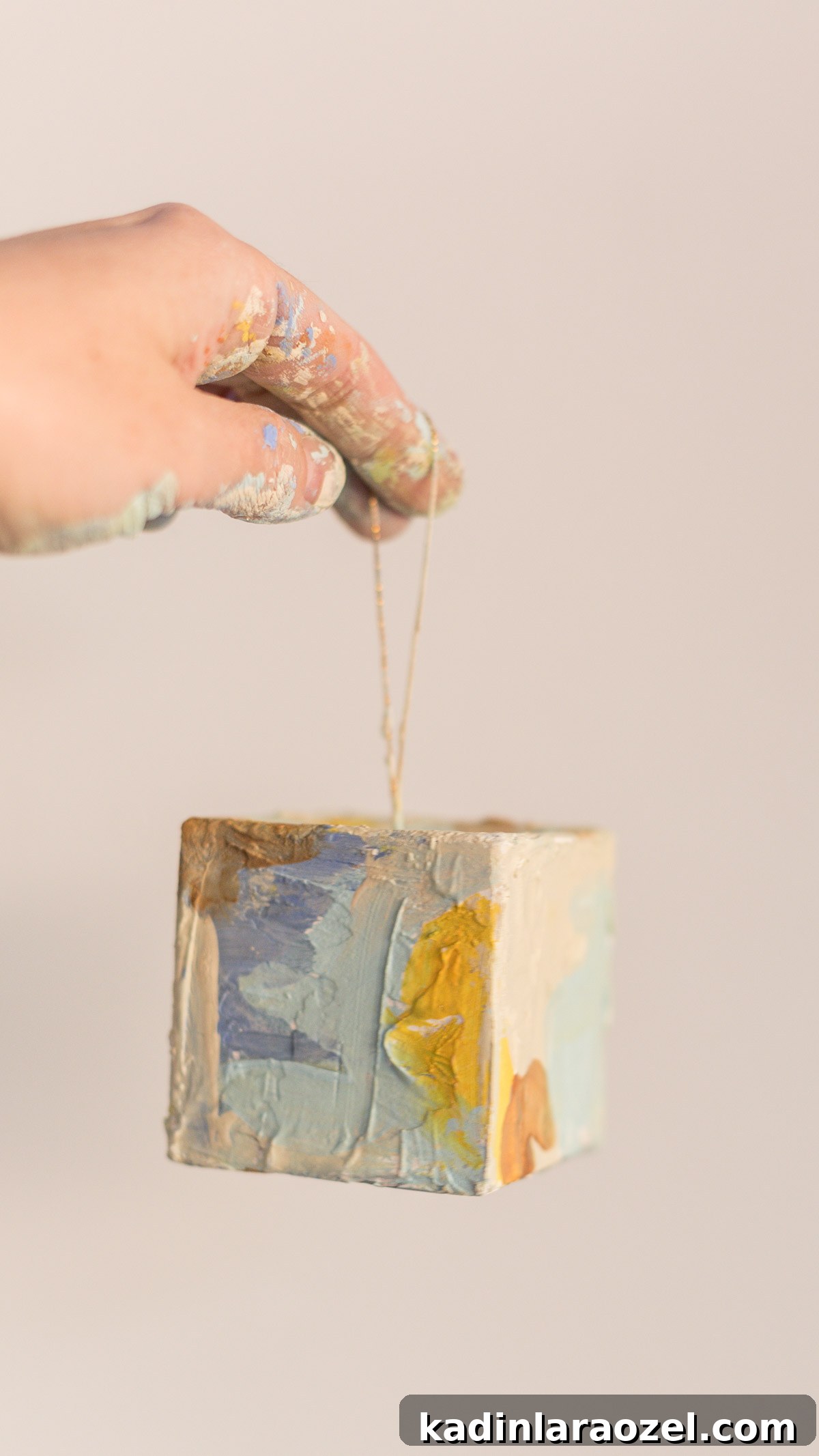 Hand holding up square shaped painted abstract ornament