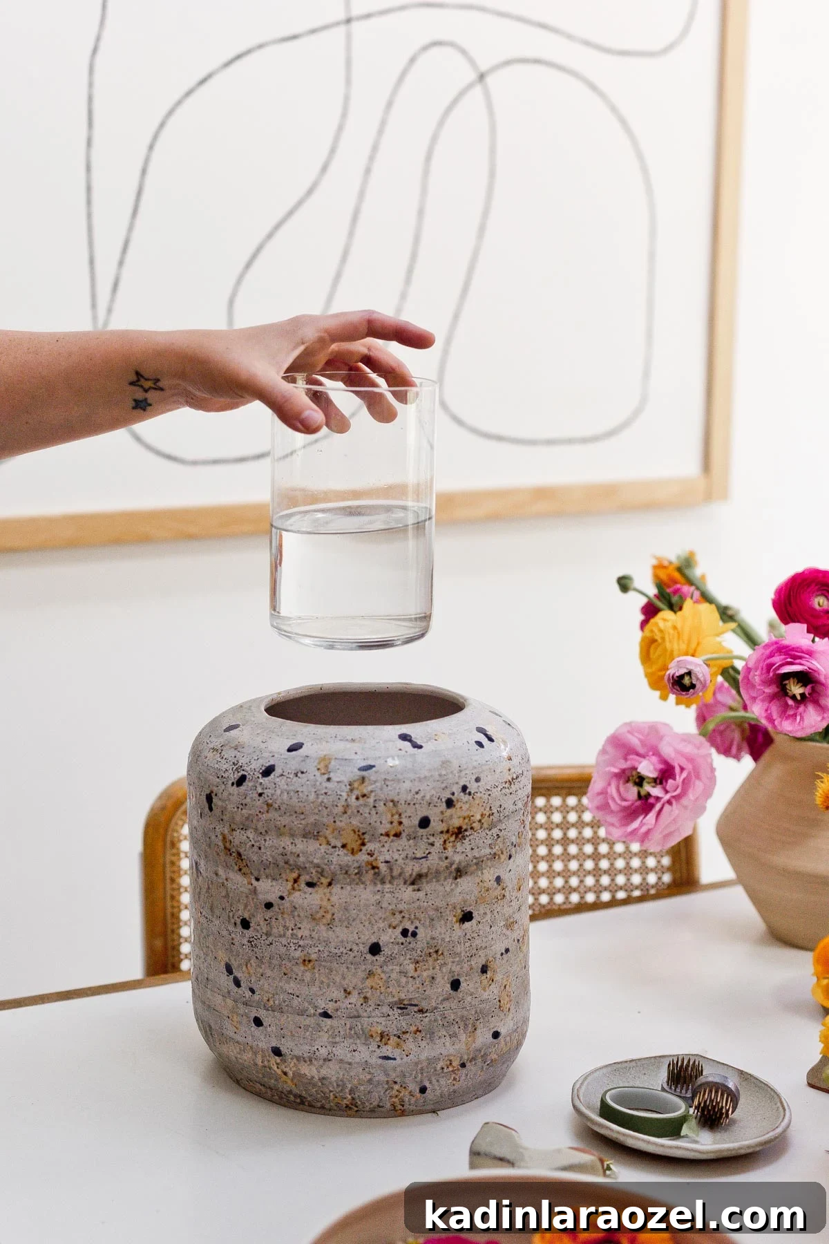 7 Pro Flower Arrangement Tips for Stunning Home Displays 5 Hand placing small vase filled with water in a larger vase on a table