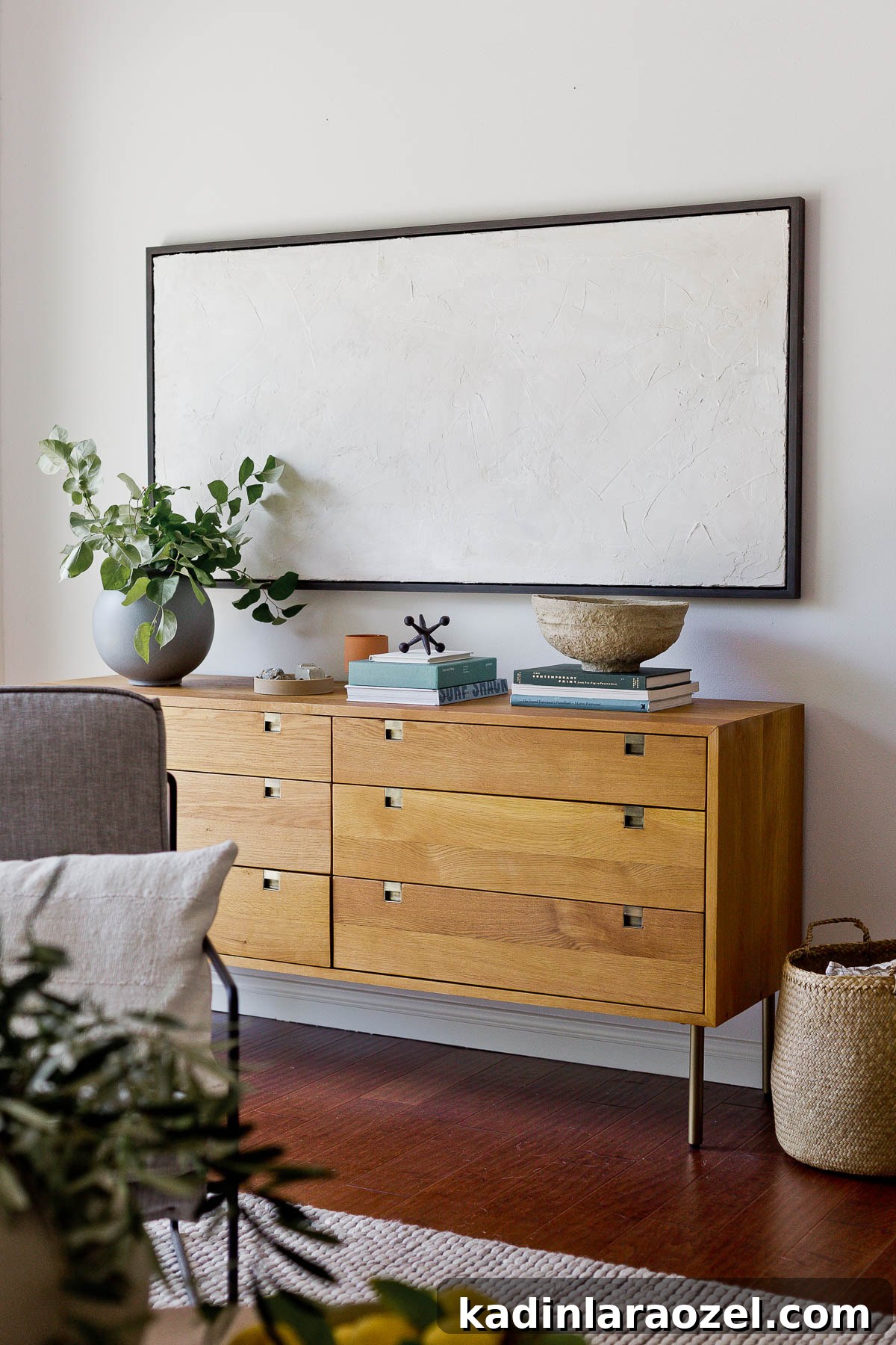 Wood dresser with gold accents in a white room with organic modern decor accessories