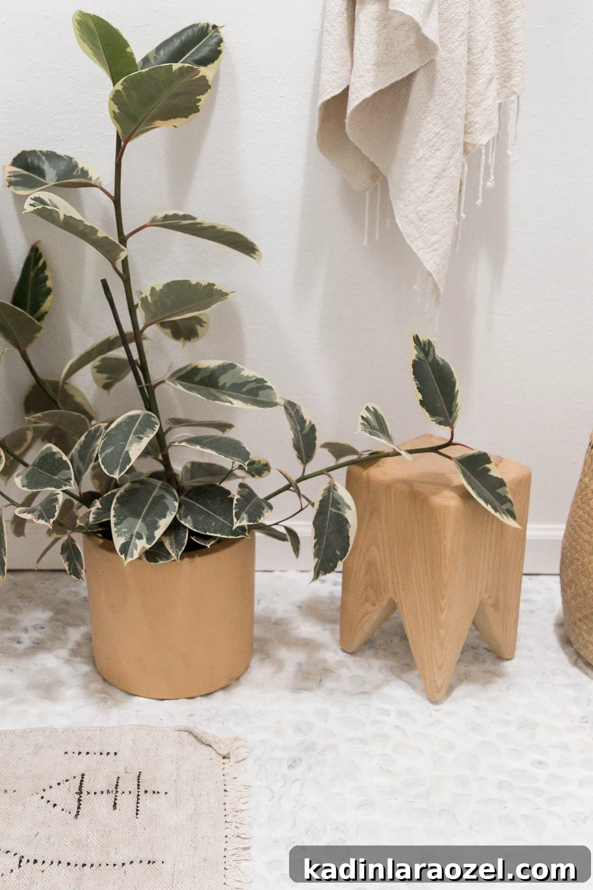 How to Paint Tile Floors: Step-by-Step Tutorial and Tips 6 Painted white river rock flooring in a bathroom with plants, a wood stool, and neutral, creamy towel