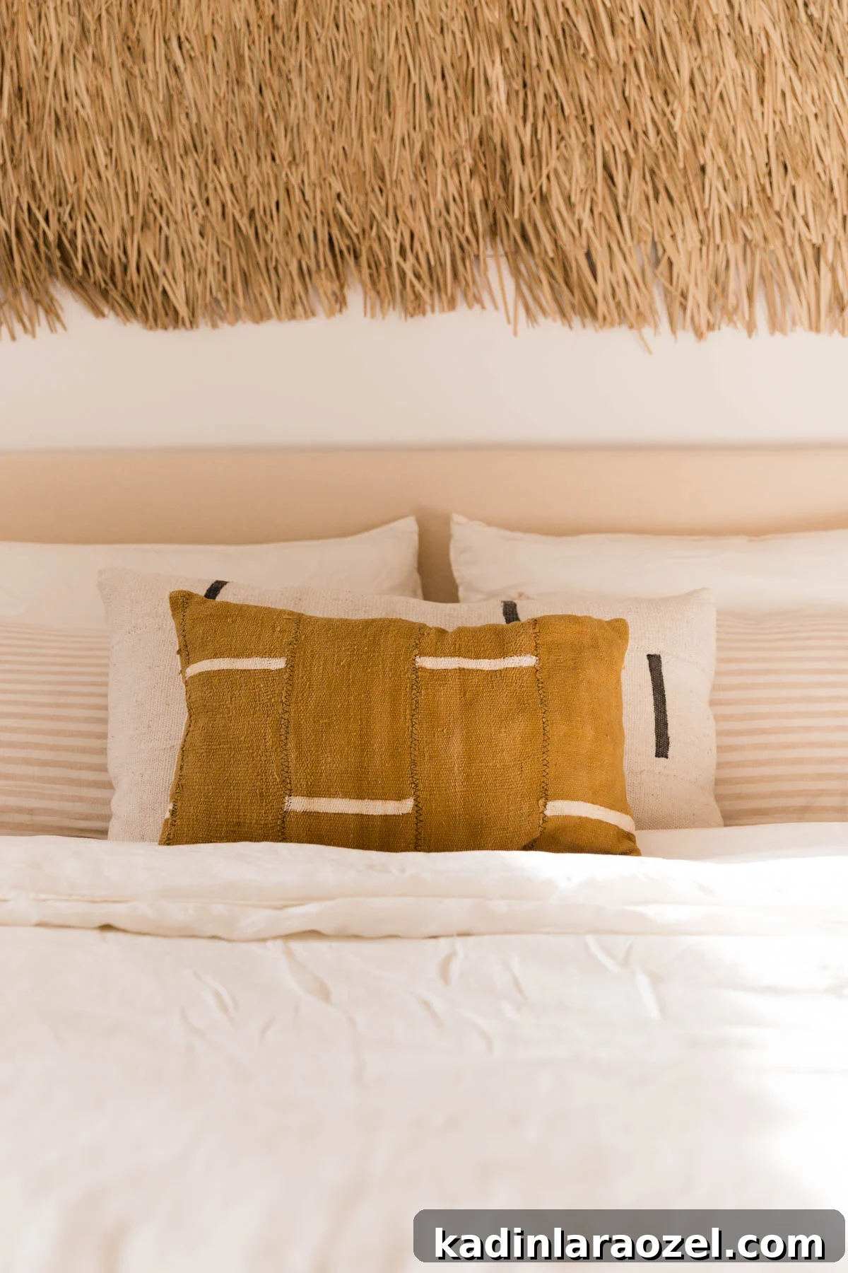 DIY Upholstered Headboard: Step-by-Step Project Guide 8 Mudcloth pillows in neutral colors and patterns on a bed with white sheets