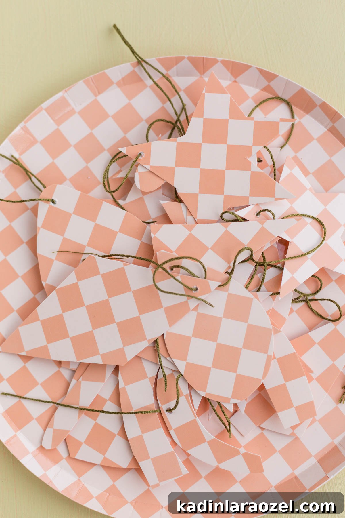diy paper ornaments in checkered patterns, sitting on top of paper plate in a pile