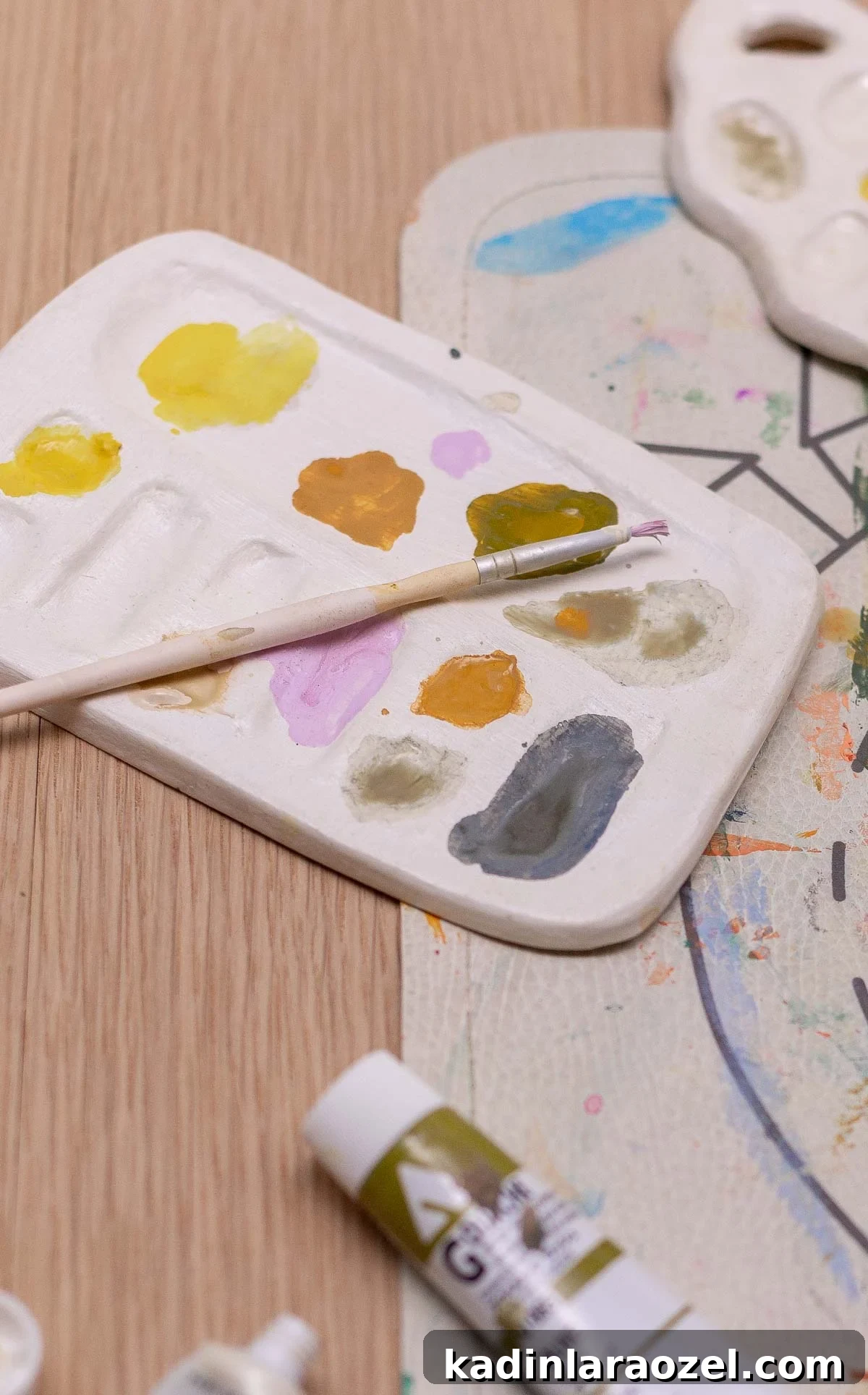handmade paint palette with pastel colors, surrounded by art supplies