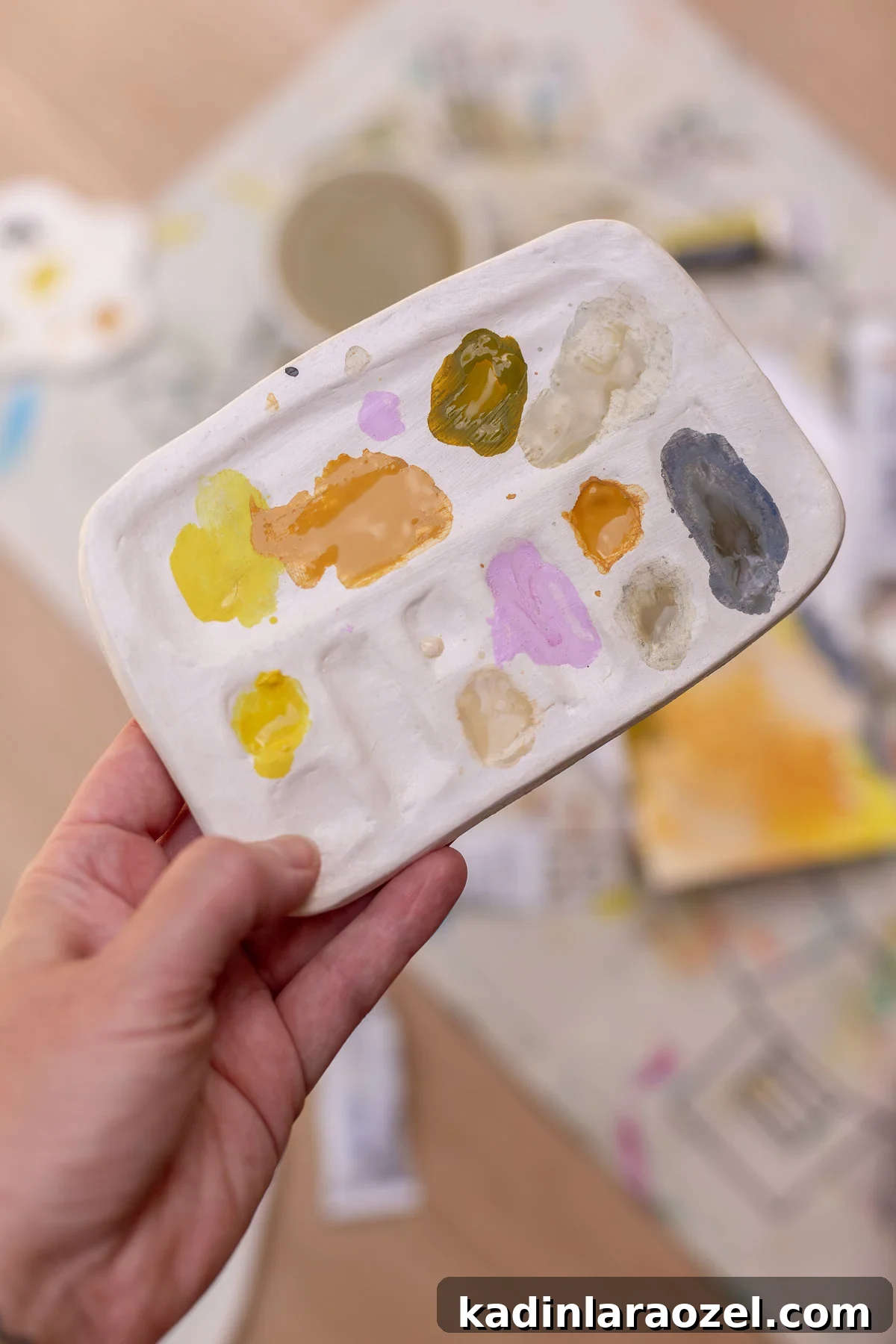 holding paint palette with pastel paints on it, in use