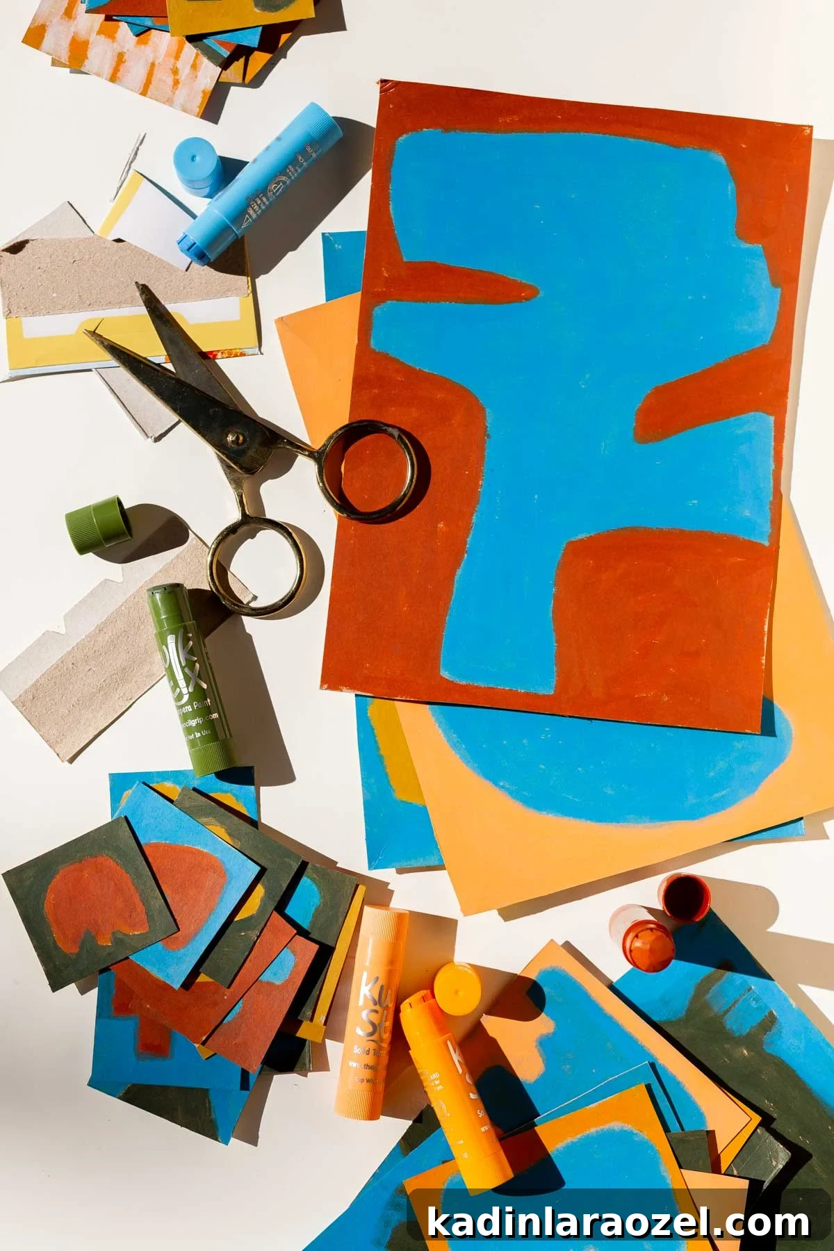 Art supplies and artwork stacked up and sprawled out on a white table