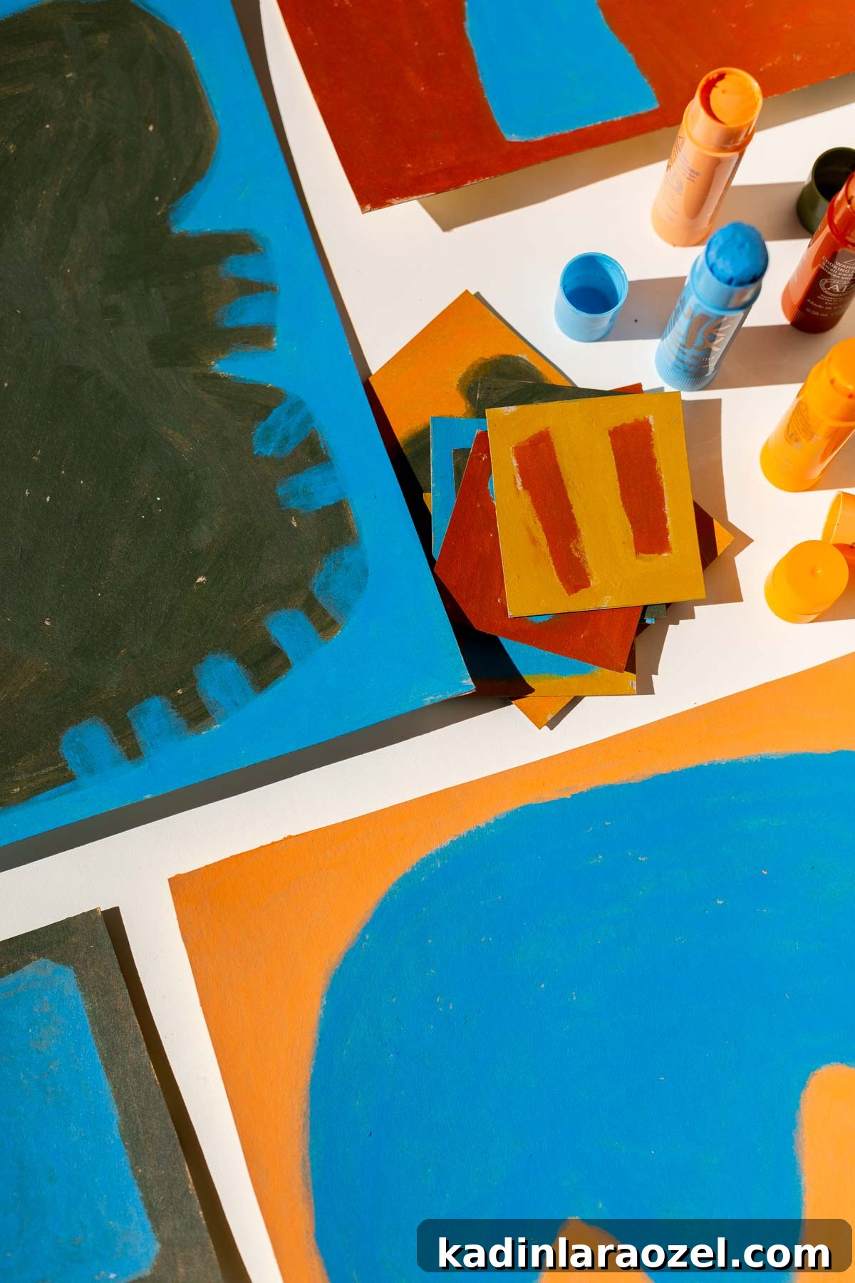Colorful abstract artwork featuring organic shapes, laid out on a white table, with overhead view