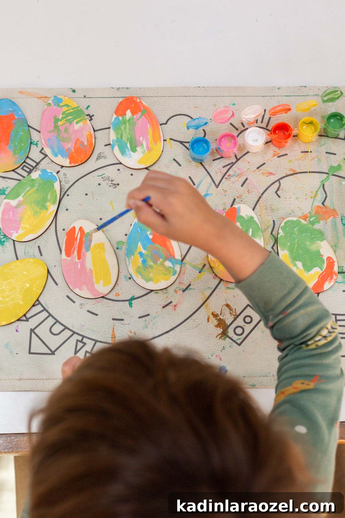 Child painting egg shaped wooden tags for Easter