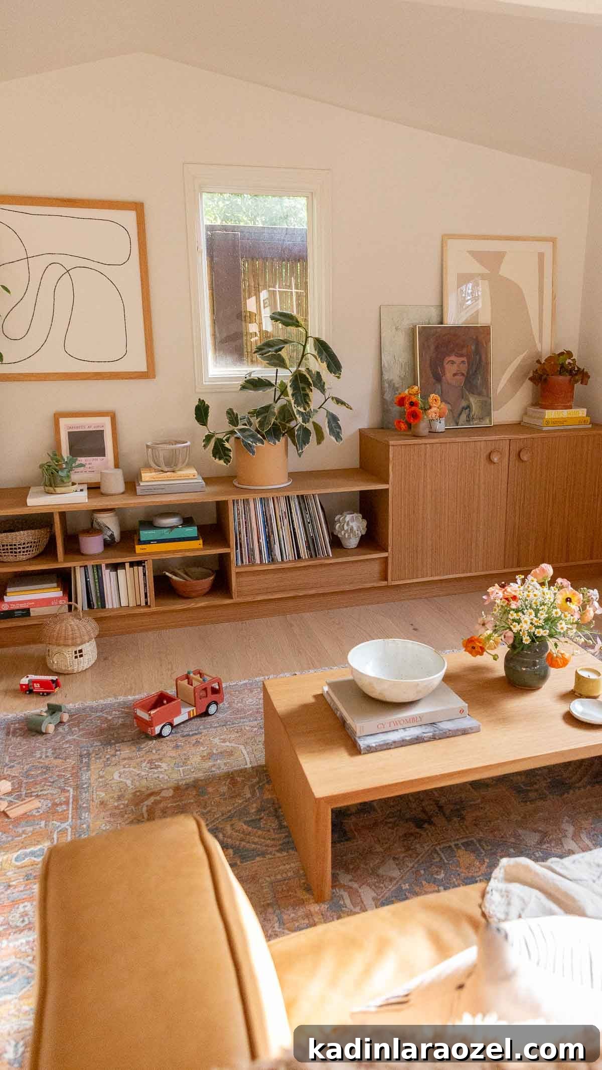 Abstract art and stacked books on wood shelving in a light-filled living room