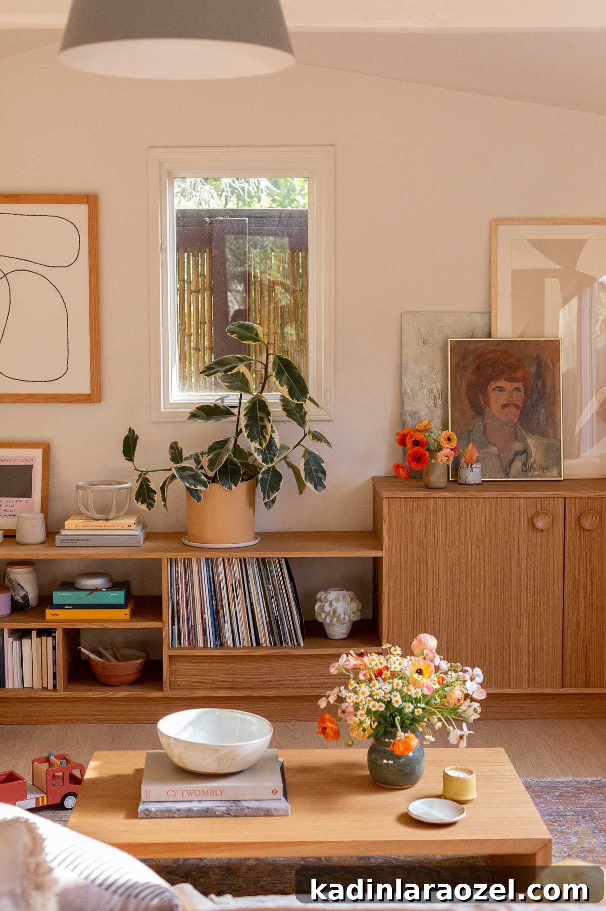 White oak built-in with plants, books, and art in a white living room with lots of natural light