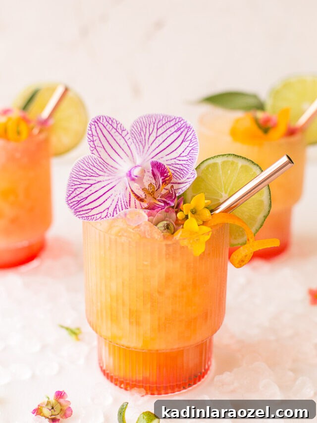17 Refreshing Summer Cocktails to Try Now 4 yellow and orange cocktail with lime slice and beautiful orchid and orange zest