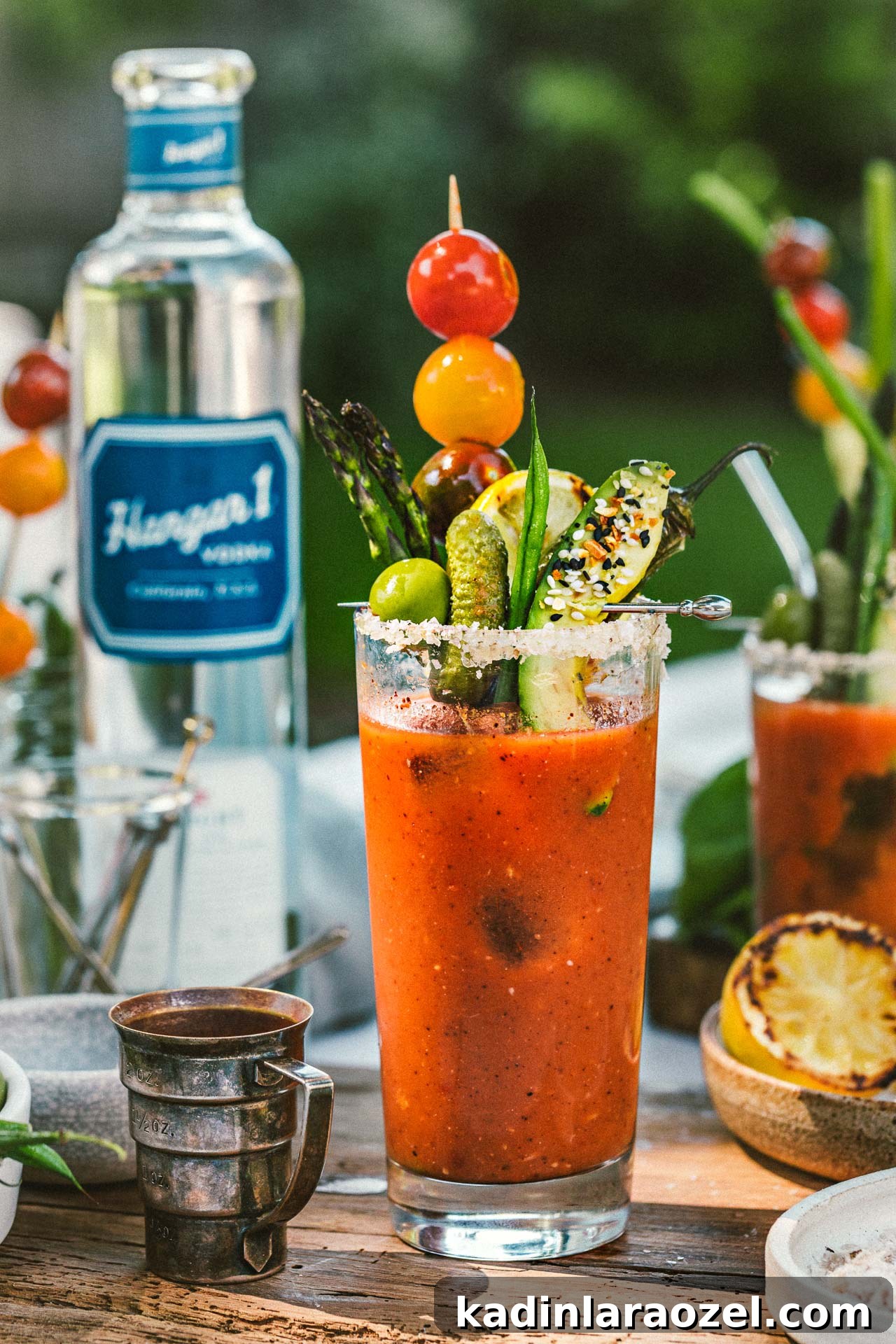 17 Refreshing Summer Cocktails to Try Now 6 bloody mary cocktail in tall glass with fresh veggie garnishes and other items on a dinner table outdoors